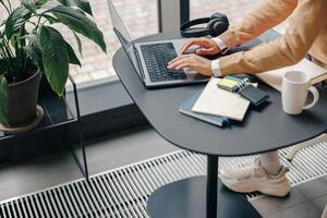Close up of female freelancer working on laptop sitting in coworking near window photo