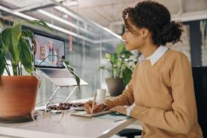 Female freelancer have conference with client and making notes sitting in cozy coworking photo