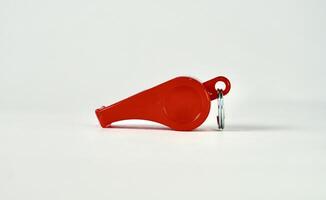 One red whistle with no string isolated on plain horizontal background from side angle view. photo