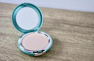Compact powder light shade make up in round box container isolated on horizontal ratio brown wooden table surface background. photo