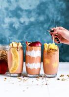 three smoothies with fruit and nuts on top photo