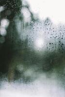 a view of a rain covered window with trees in the background photo