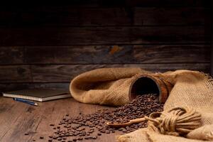 The picture of coffee beans stacked together on a wooden floor in a warm, light atmosphere, on a dark background, with copy space. photo