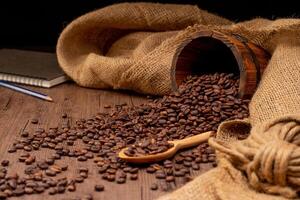 The picture of coffee beans stacked together on a wooden floor in a warm, light atmosphere, on a dark background, with copy space. photo