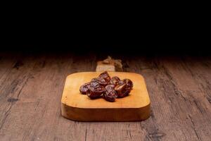 Many Date Palms are on bowls, plates, and cups of water, and the Quran is on wooden tables, to wait for the time of Iftar, with the concept of ramadan Muslims, Arabic calligraphy meaning of Al Quran photo