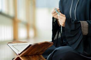 The image of an Asian Muslim woman in the Islamic religion in hijab in cream color. reading the Quran and having a happy smiling face Staying in a beautiful mosque out of respect for God. photo