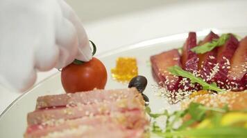tranché Bacon avec sésame est décoré avec Cerise tomate près pièces de salé à sec Viande et citron avec Olives et coriandre sur une transparent assiette sur le flou Contexte dans le café. video