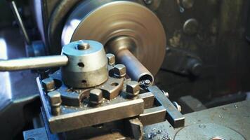 A lathe processes metal blank in the factory. Shavings fall to the floor in the room.Close-up. video