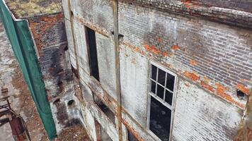 Damaged brick building without windows after the war. Close view of a destructed house with many holes in the wall. Camera moves top down video