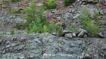 A tourist with a backpack walks around the lake on the background of a quarry on a warm day. Gray background. Camera motion to right. video