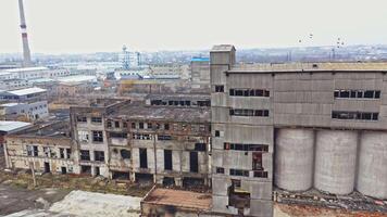 A huge state-owned factory with gray walls and broken glasses in the windows on the background of city buildings. Industrial zone. Aerial view. video