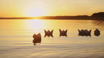 Many nice homemade paper boats floating in the river with a beautiful sunset background. Ships made from paper swimming on the water surface in the evening video