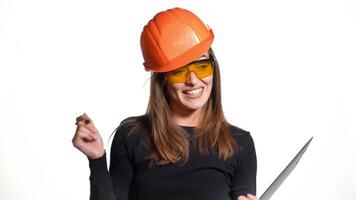 Pretty woman engineer in an orange helmet tells a story about something and holds a folder-tablet with pen in her hands on a white background. video