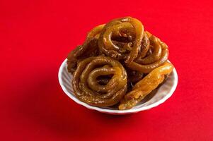 Indian sweet jalebi, indian dessert jalebi or imarti or imarati or jilbi on red background photo
