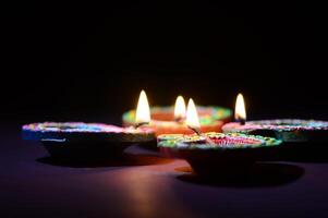 Four lit diyas on a dark surface photo