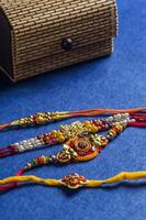 Three rakhi's with a wooden box on a blue surface photo