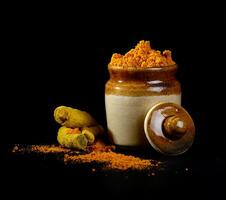 Tumeric powder in a jar on a black background photo