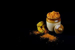 A jar of tumeric and a spoon of tumeric photo