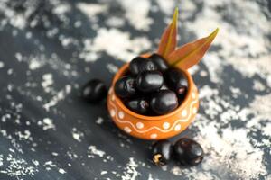 Jambolan plum or jambul or Jamun fruit, Java plum, Syzygium cumini with leaf on stone textured background. photo