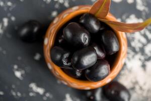 Jambolan plum or jambul or Jamun fruit, Java plum, Syzygium cumini with leaf on stone textured background. photo