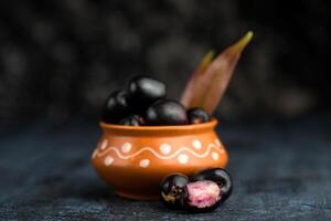 Jambolan plum or jambul or Jamun fruit, Java plum, Syzygium cumini with leaf on stone textured background. photo