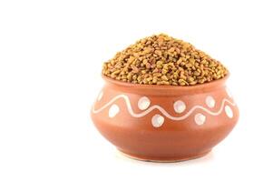 Fenugreek seeds in clay pot isolated on white background photo