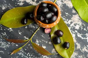 Jambolan plum or jambul or Jamun fruit, Java plum Syzygium cumini with leaf on stone textured background. photo