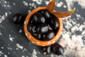 Jambolan plum or jambul or Jamun fruit, Java plum Syzygium cumini with leaf on stone textured background. photo