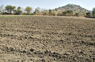 A field with dirt and a hill in the background photo