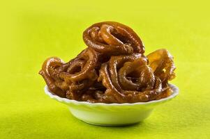 A bowl of fried onion rings sitting on a green surface photo