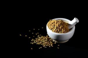Coriander Powder and seeds with mortar and pestle on black background. photo