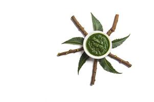 Medicinal Neem leaves with paste in bowl and twigs on white background photo