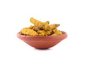 Dry Turmeric roots or barks in clay pot isolated on white background photo