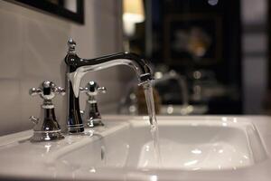 Water running from a chrome bathroom faucet into sink photo