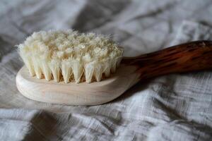 Natural bristle body brush lying on soft fabric for relaxation photo
