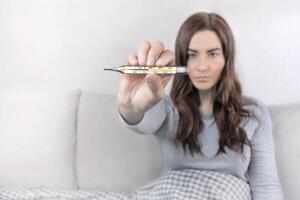 Woman shows mercury thermometer with a temperature of 37,7 C. Copy space photo