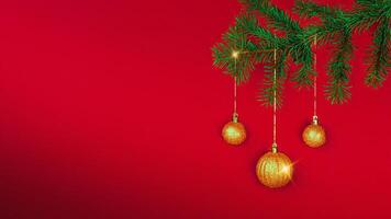 Golden Christmas balls sparkle on the Christmas tree branch on a red background. New Year's card, banner, copy space photo