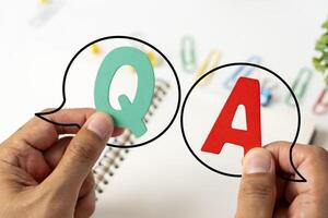 Q and A written on a notepad Work desk with electronic equipment computer and paper wooden table from above. photo