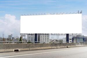 Empty billboard on the side of a highway. The billboard is located in a city, and it is facing the highway. The billboard is large and rectangular. photo