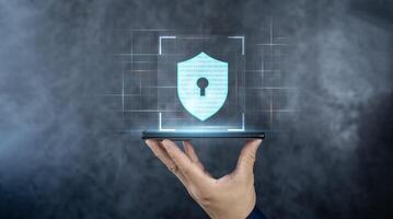 Cyber security technology and data protection privacy concepts. Shield icon on futuristic transparent smart mobile phone in hand surrounded with binary code. photo