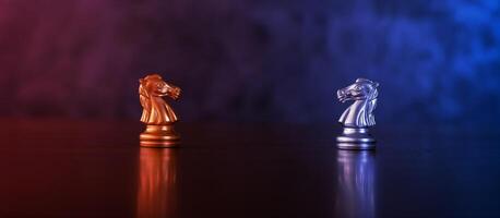 Chess pieces knights facing each other for a standoff. Chess knights confronting each other. Chess knights head to head. Chess horses face each other in warm and cold tones. photo