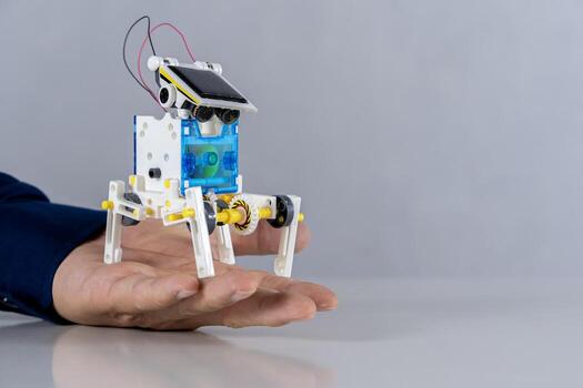 A plastic robot is in the hand of a student placed on the table, experimenting with learning with his hands, improving his skills. photo