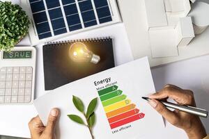 Energy efficiency concept with energy level chart Tabletop energy efficiency graph with house diagram calculator Solar panels. Businessman planning to use energy. photo