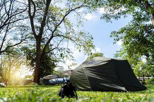 Camping picnic green tent campground in outdoor hiking forest. Camper while campsite in nature background at summer trip camp. photo