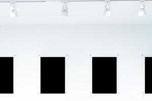 A row of black frames hang on a white wall, clipping path. They are all made of different materials. The frames add interest. photo