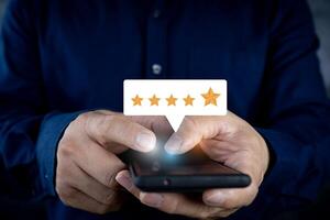 Close up on Customer Man hand pressing on smartphone screen with golden five star review icon and excellent rating for best rating in service review. photo