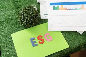 Green paper with the word ESG written on it. The paper is green and has a graph on it. The graph shows three lines, one for each of the three ESG factors photo