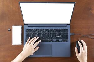 Close up businesswoman using smartphone and laptop with empty white blank screen mockup, sitting at desk, employee worker consulting client online. photo