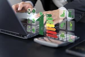 Energy efficiency concept. Businessman using laptop with energy efficiency rating symbol photo