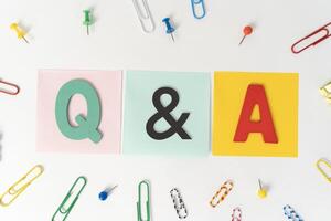 Top view of colorful post-it notes with top written with Q A or questions and answers on white background. photo